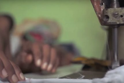 Criança trabalha com máquina de costura em confecção: atividade perigosa agrava a violação de direitos.