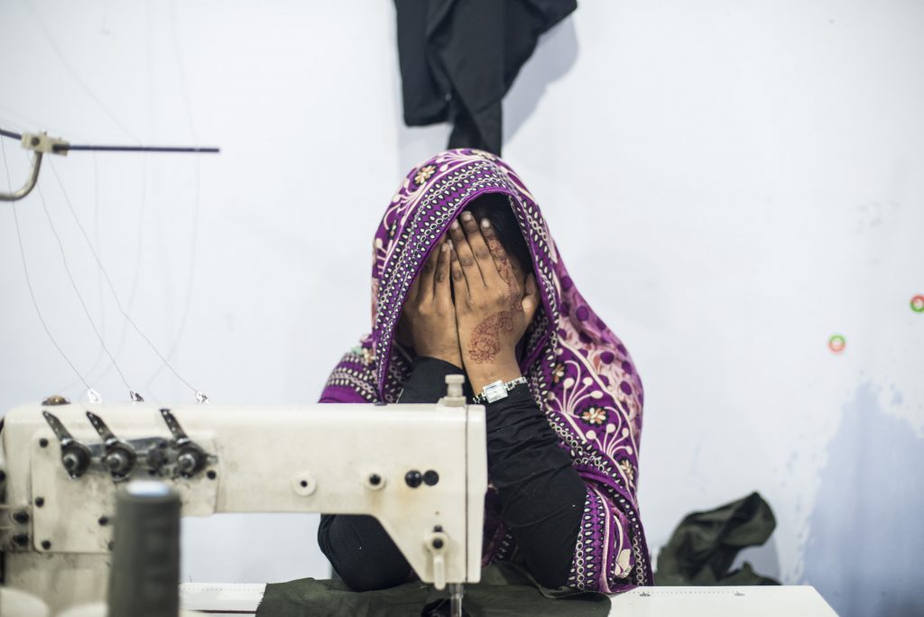Menina esconde o rosto em fábrica de roupas de Daca, Bangladesh