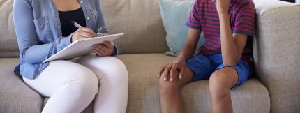 Qual é o papel do psicólogo no combate ao trabalho infantil? A foto mostra uma prossional conversando com um garoto, ambos sem identificação dos rostos, para preservar a imagem. Crédito: iStock